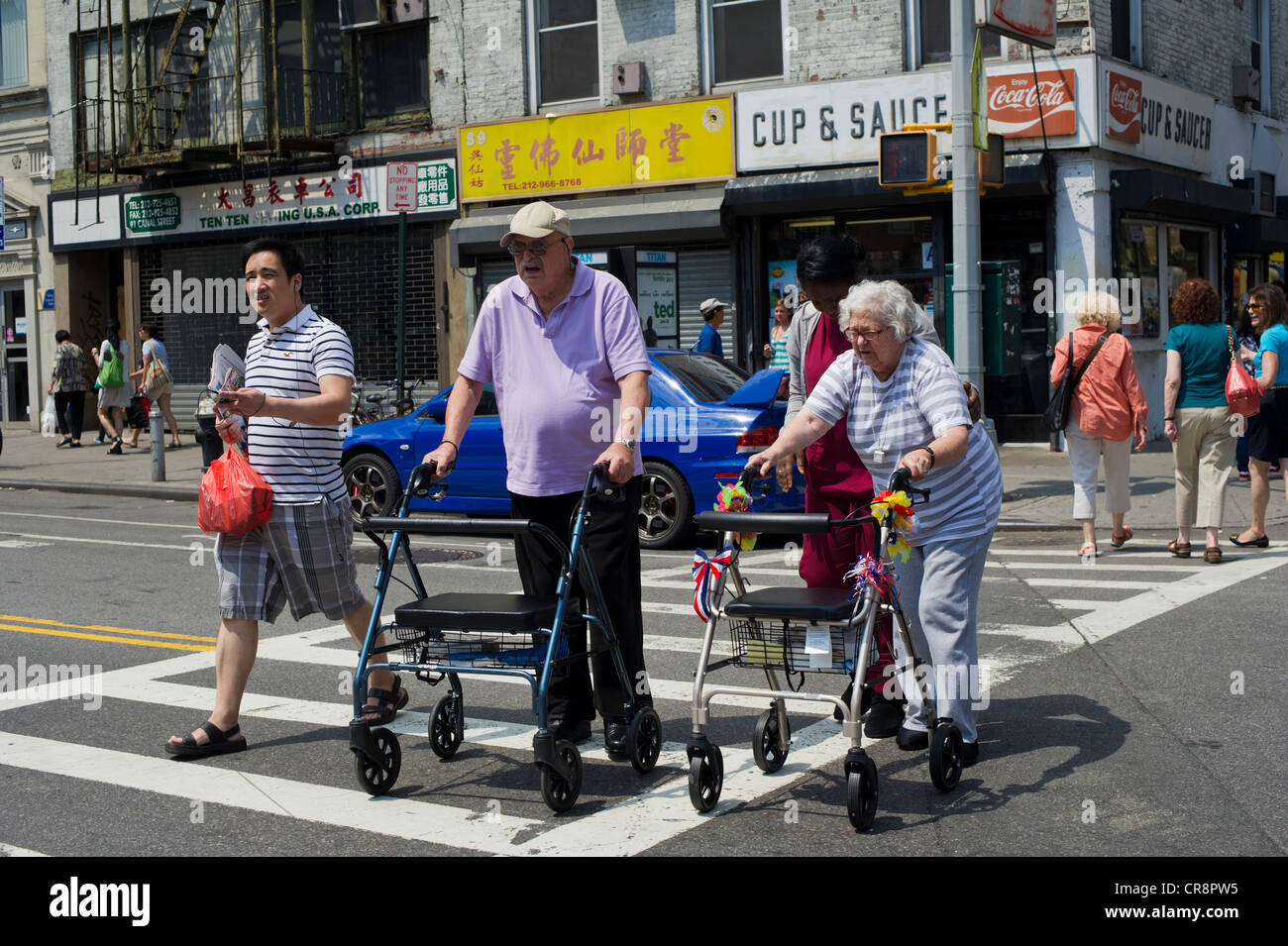 Ein älteres Ehepaar mit ihren Adjutanten kreuzt eine Kreuzung in lebhaften Chinatown in New York Stockfoto