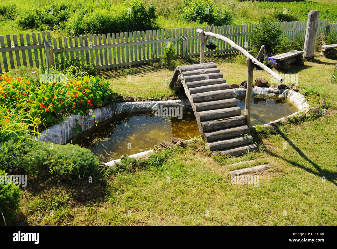 kleiner Gartenteich mit Holzbrücke im Sommer Stockfoto