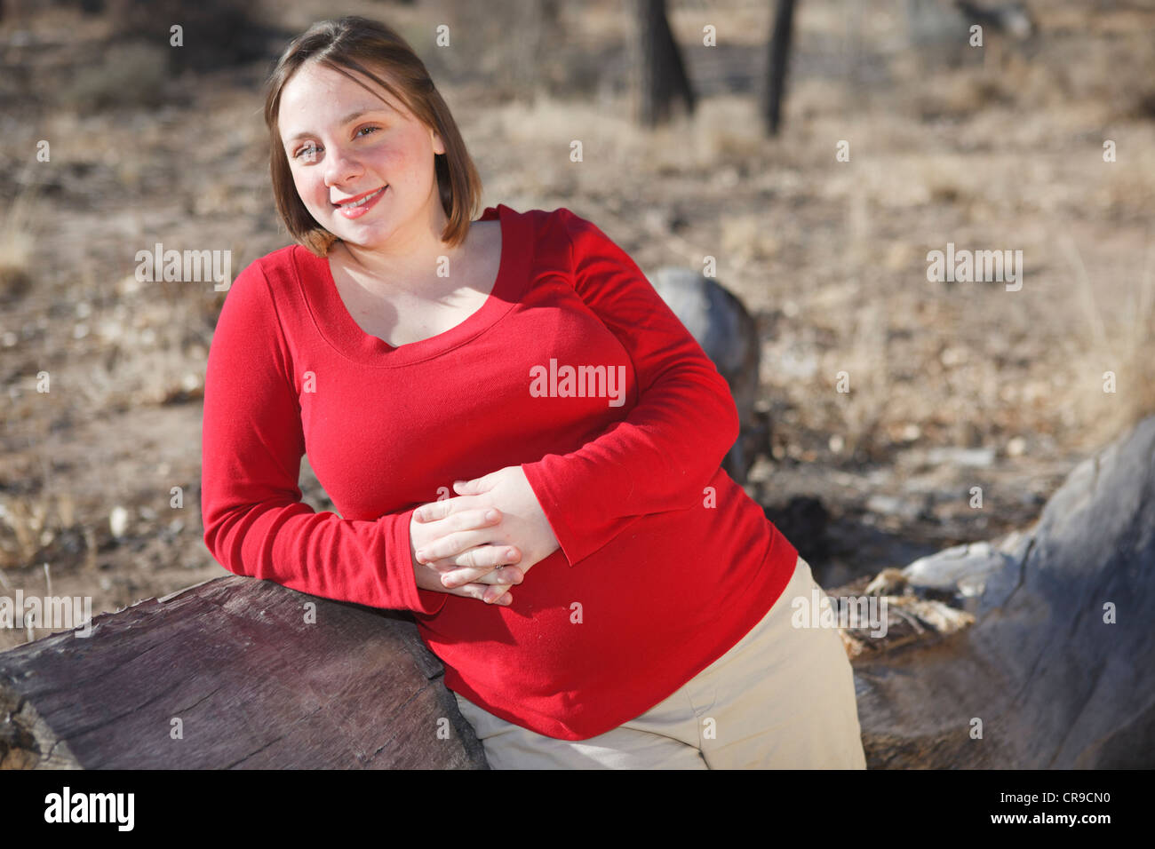 Junge 8 Monate schwangere junge Frau stand neben einem Protokoll im freien trägt ein rotes Hemd. Stockfoto