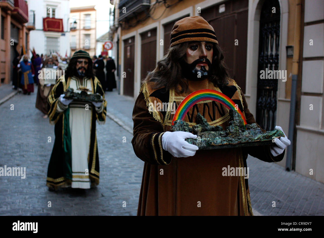 Ein maskierter Mann gekleidet wie eine biblische Figur ein Relikt während einer Prozession der Karwoche in Puente Genil, Spanien hält Stockfoto