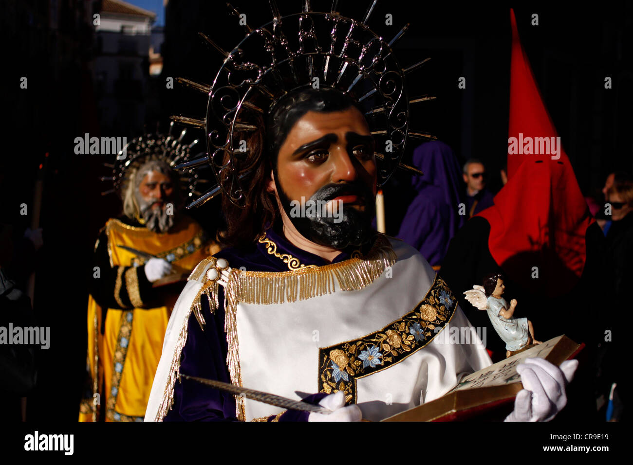 Eine maskierte Männer gekleidet als Matthaeus ein Relikt während einer Prozession der Karwoche in Puente Genil, Spanien hält Stockfoto