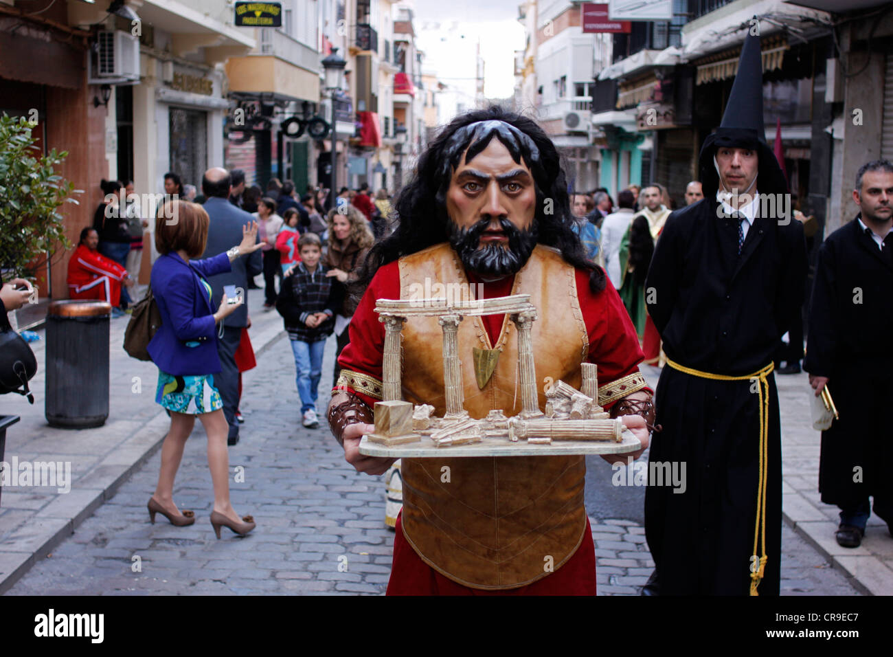 Ein maskierter Mann gekleidet wie eine biblische Figur ein Relikt während einer Prozession der Karwoche in Puente Genil, Spanien hält Stockfoto