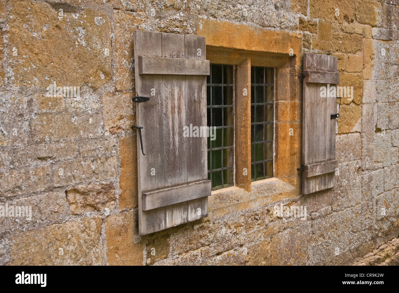Rollläden an Fenstern inmitten einer alten Steinmauer Cotswold Stockfoto