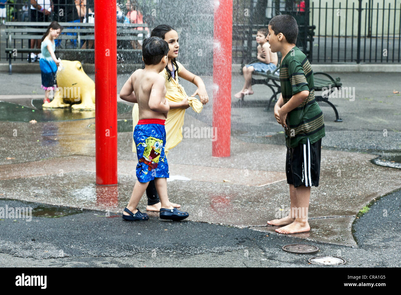 Stadtkinder in einweichen nasse Straßenkleidung viel Spaß im Wasser-Feature im DeWitt Clinton Park Hells Kitchen New York Stockfoto