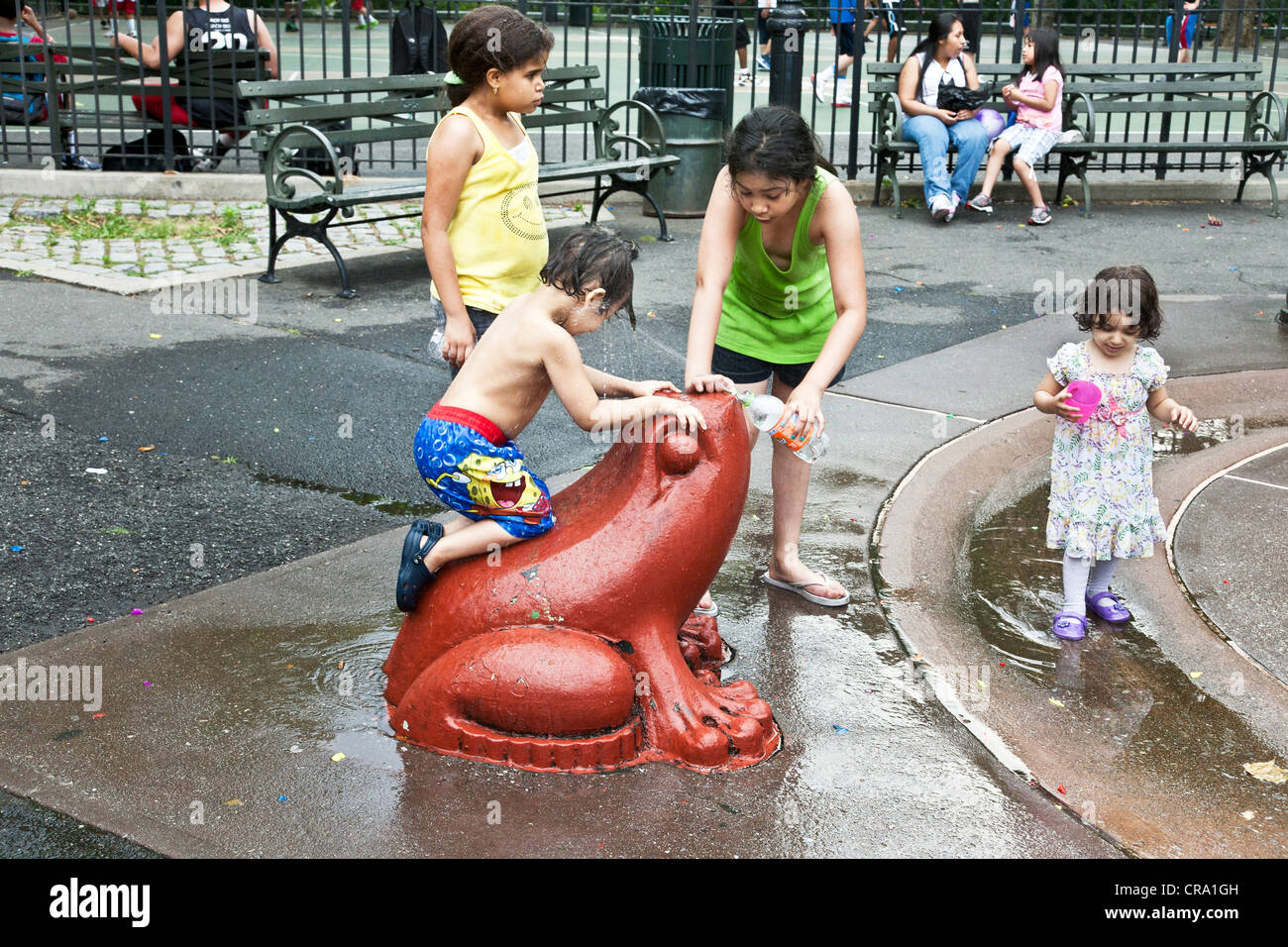 glückliche Gruppe von multiethnischen Kinder spielen auf bunten Frosch im Wasser-Funktion von DeWitt Clinton Park in Höllen Küche Nachbarschaft Stockfoto