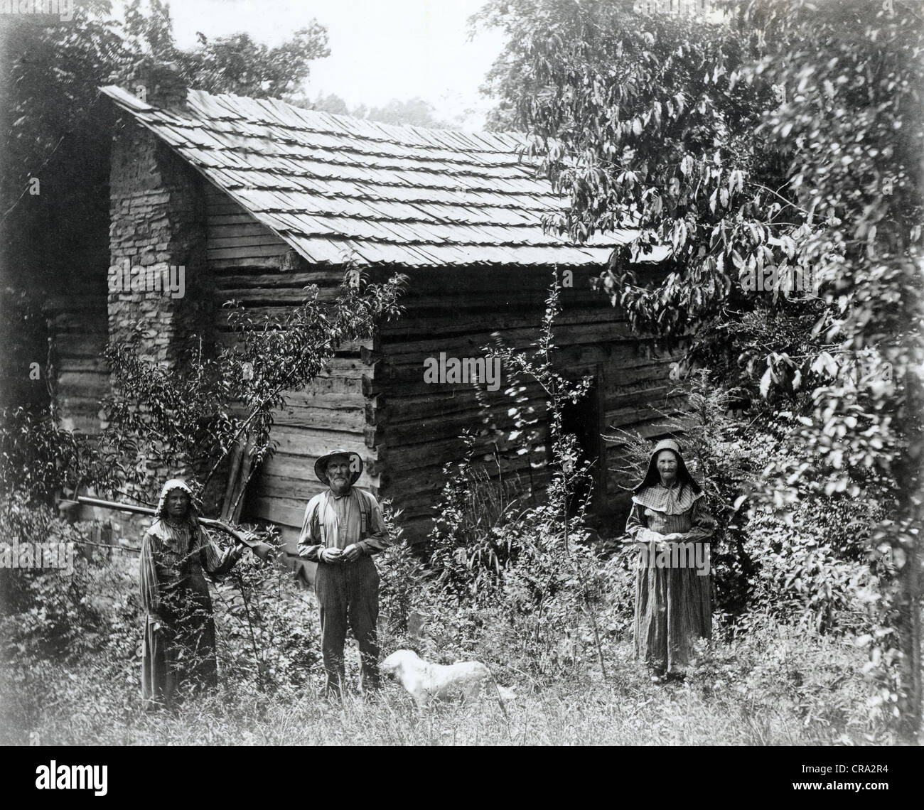 Ältere paar & erwachsene Tochter vor alten Log Cabin Stockfoto