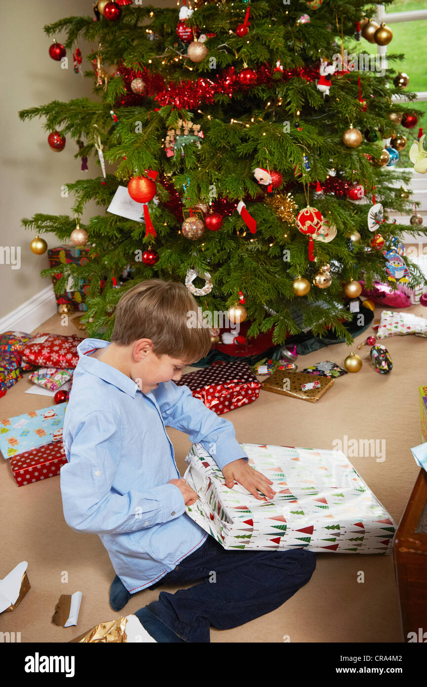 Lächelnde junge Weihnachtsgeschenk öffnen Stockfoto