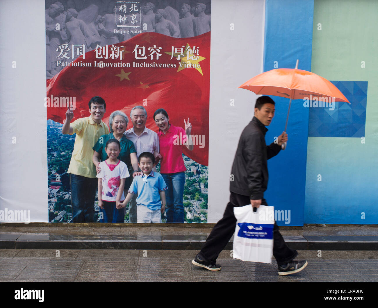 Mann zu Fuß vorbei an patriotische Propaganda-Plakat in Peking China Stockfoto