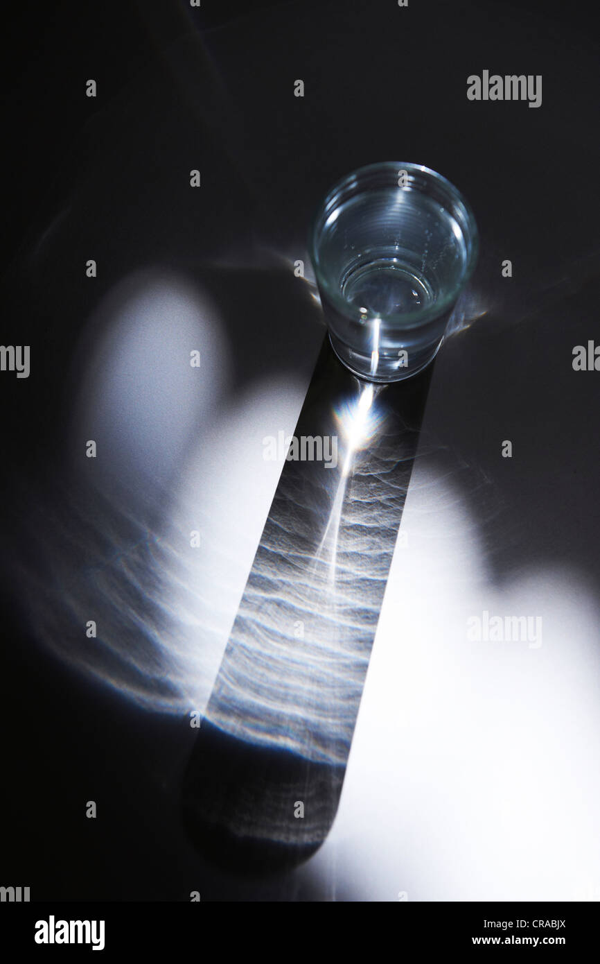Glas Wasser in einem Strahl von Licht Stockfoto