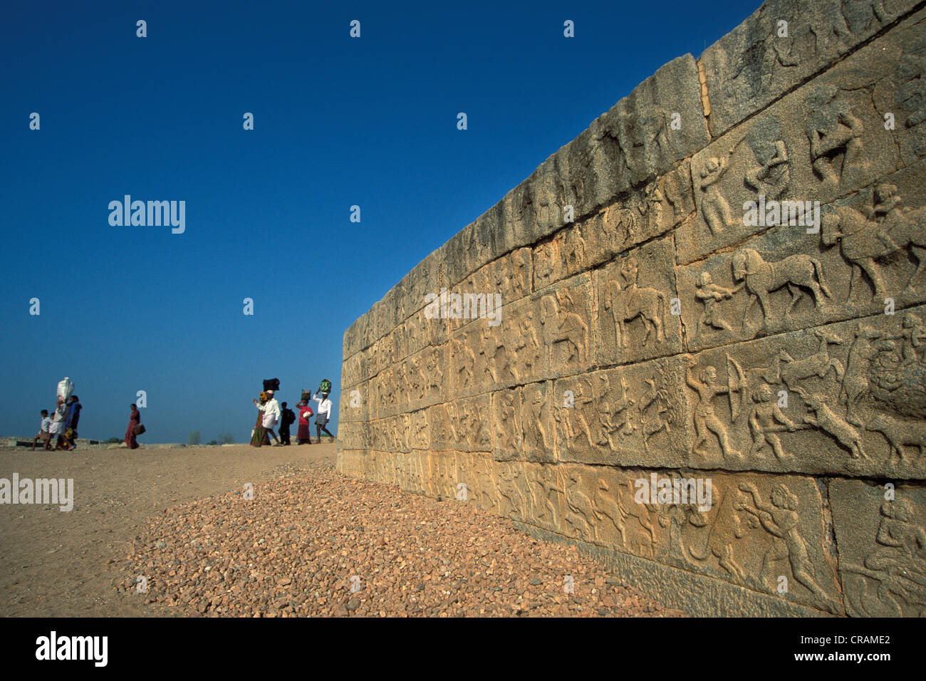 Indische Gruppe von Besuchern, Wand mit Reliefs von Jagdszenen, Hampi, die Ruinen der hinduistischen Königreich von Vijayanagar, Karnataka Stockfoto