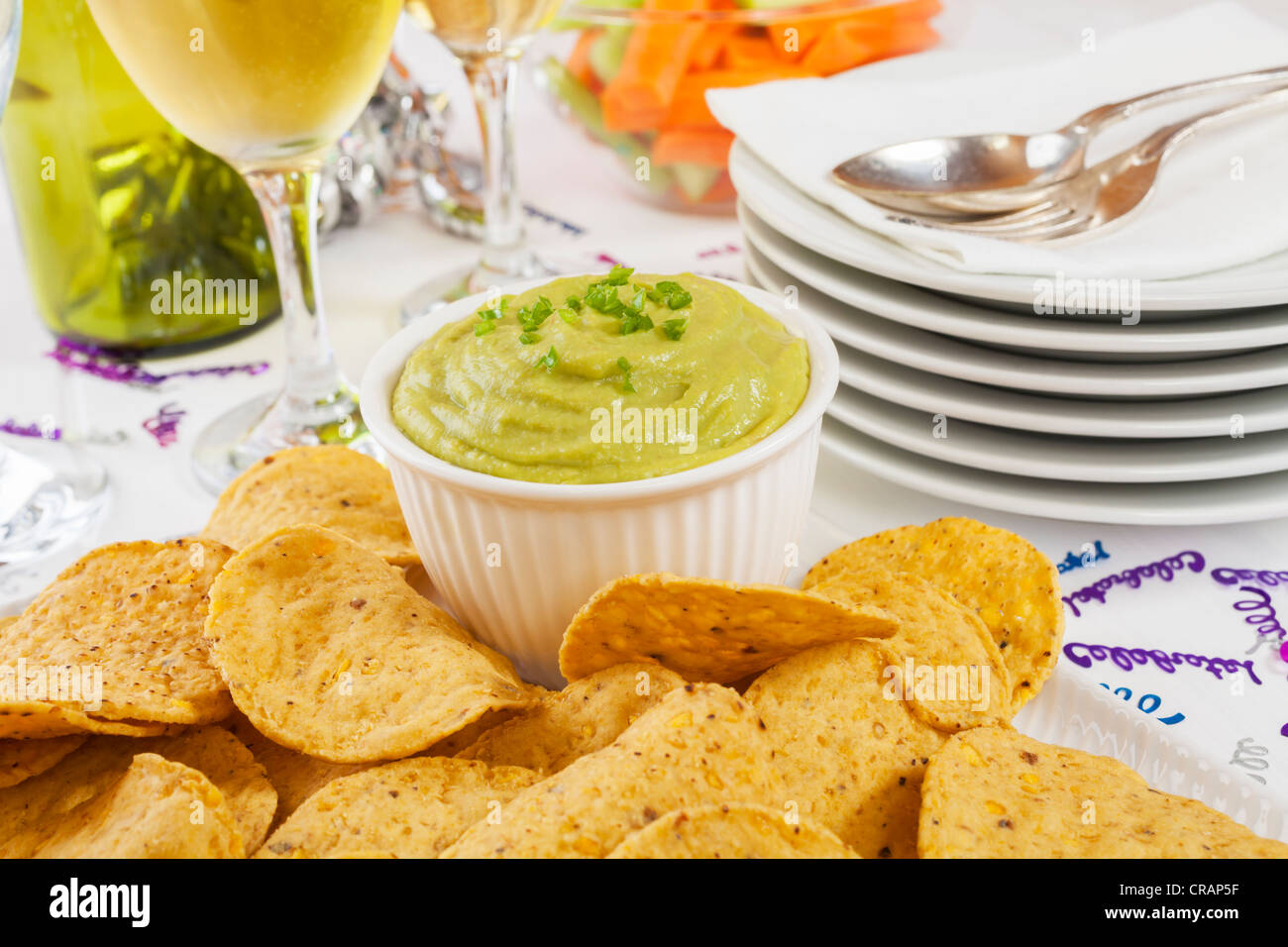 Guacamole garniert mit frischen grünen Chili mit Mais-Chips zum Dippen, begeben sich auf eine Tabelle bereit für eine Party oder Feier. Stockfoto