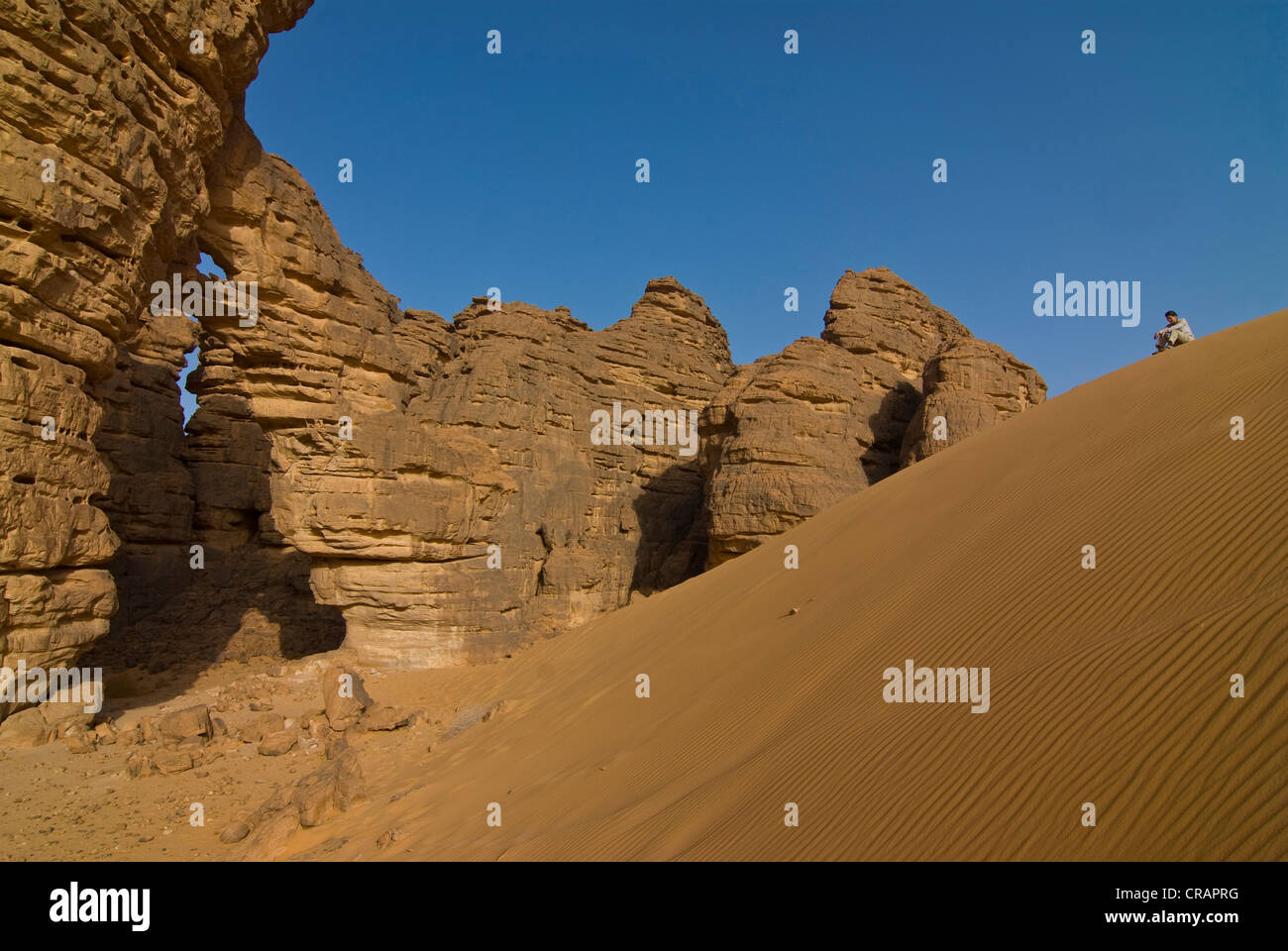 Frau vor einem Felsbogen in der Wüste in der Nähe von Tikoubaouine, Algerien, Afrika Stockfoto