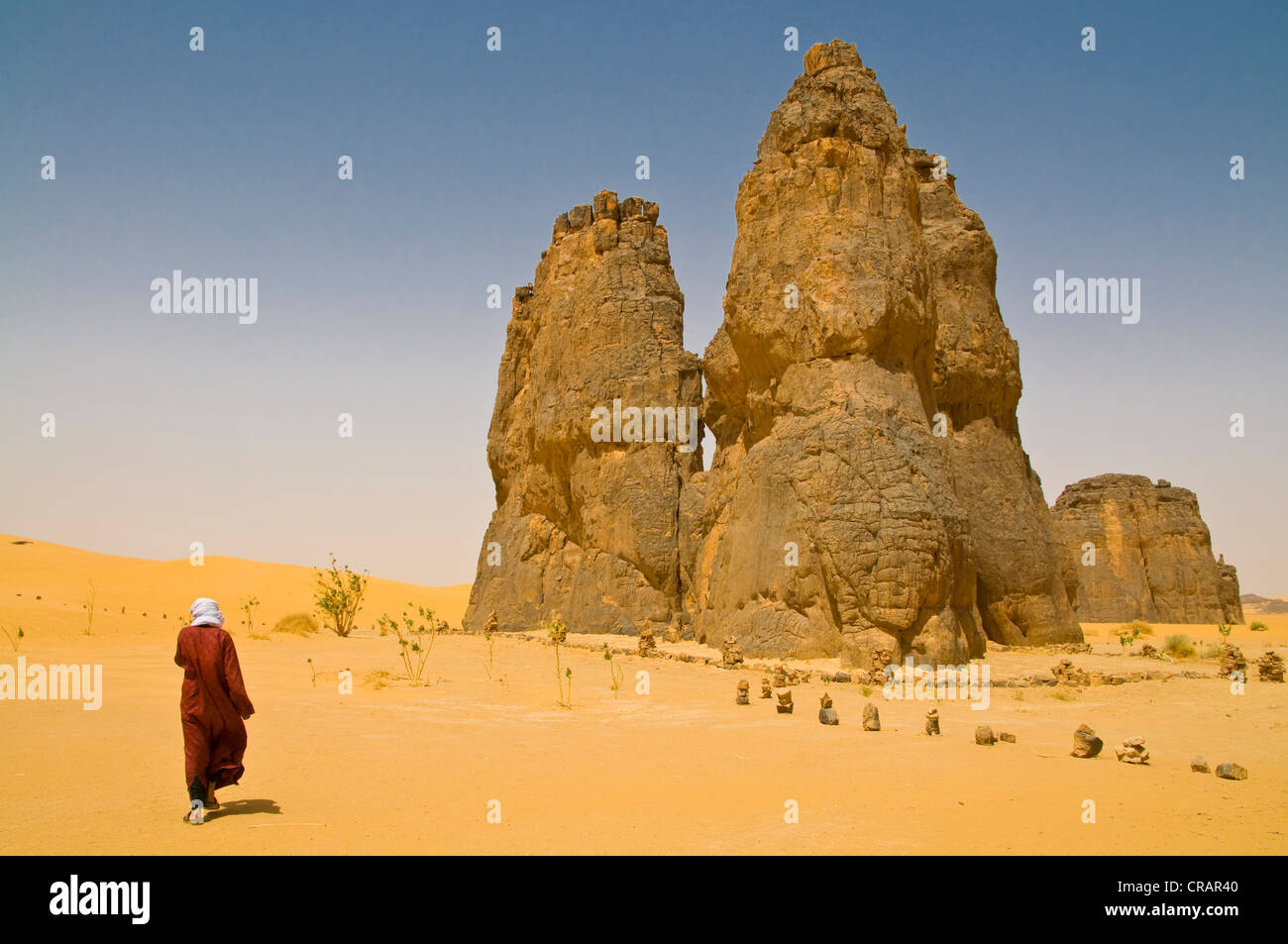 Mann zu Fuß in Richtung einer Felsformation in der Wüste Sahara, La Vache Qui Pleure, Algerien, Afrika Stockfoto