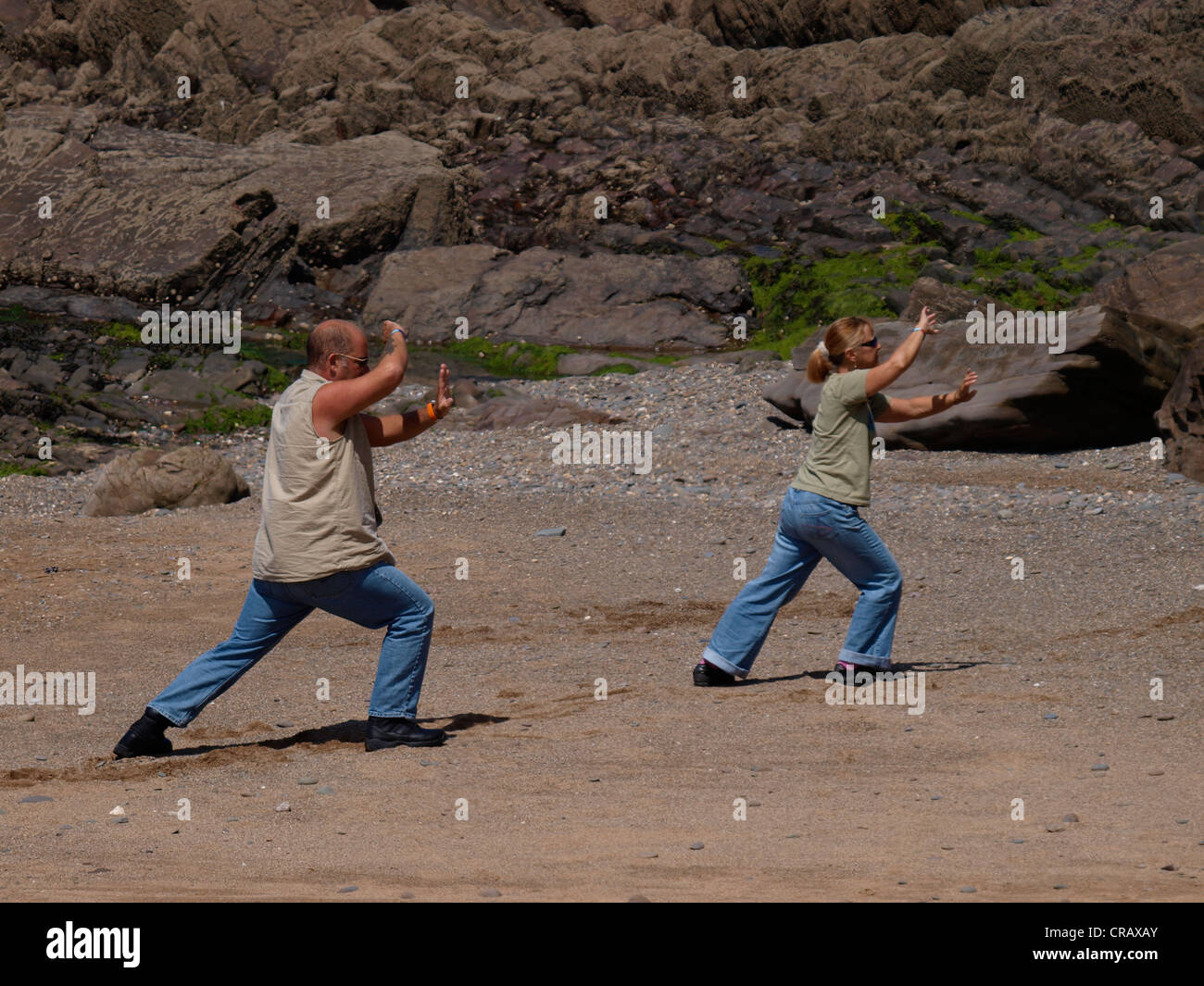 Paar praktizieren Tai Chi am Strand, Cornwall, UK Stockfoto