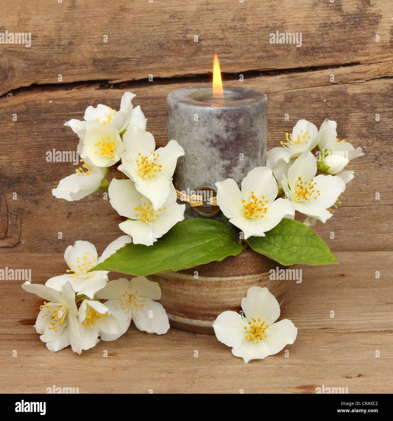 Brennende Feng Shui Kerze mit weißen Philadelphus Blumen vor dem Hintergrund der alten geknackt und verwitterte Holz Stockfoto