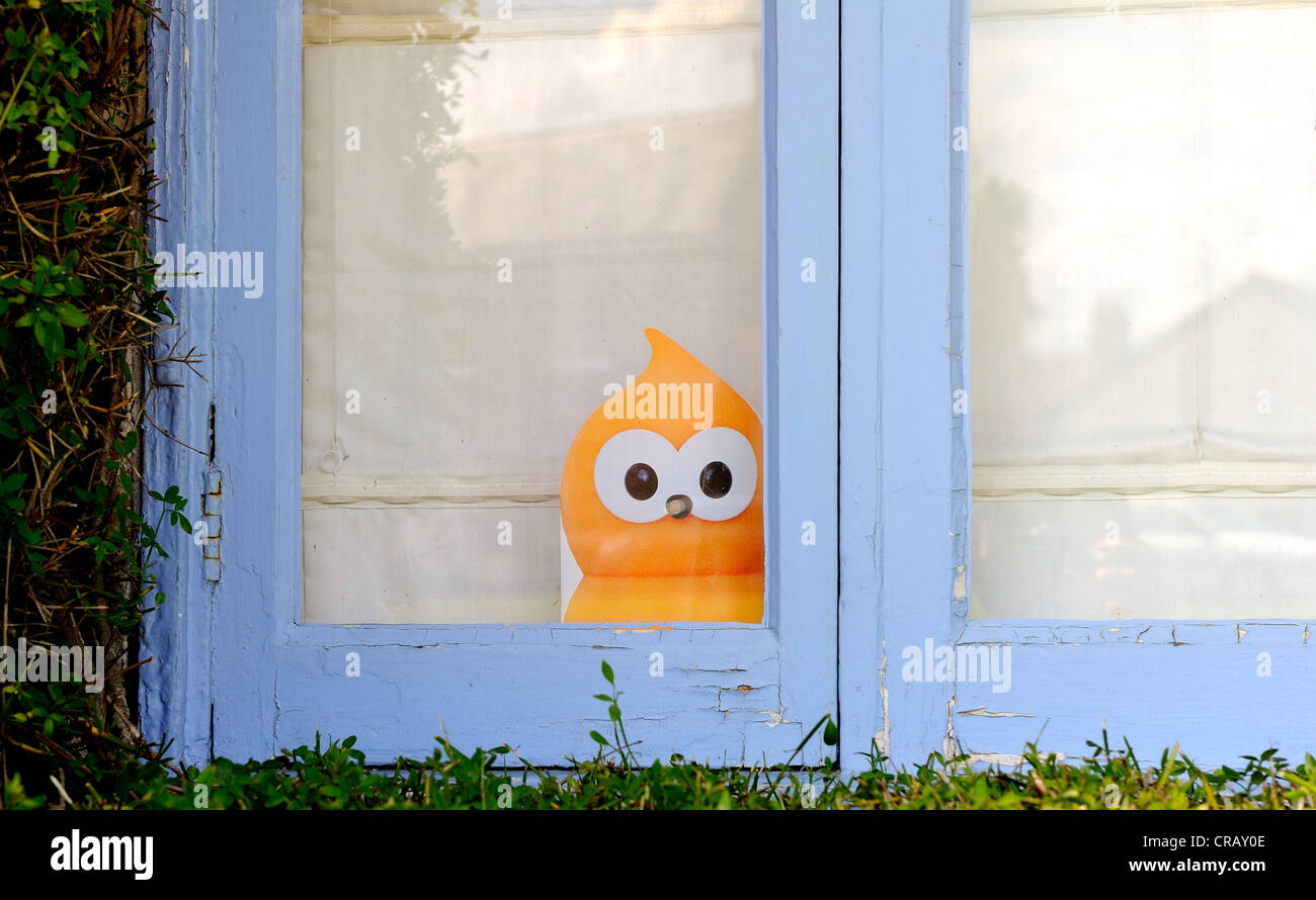Das EDF Energie orange Flamme Maskottchen namens Zingy umrahmt von leichten blauen hölzernen Fensterrahmen. Stockfoto