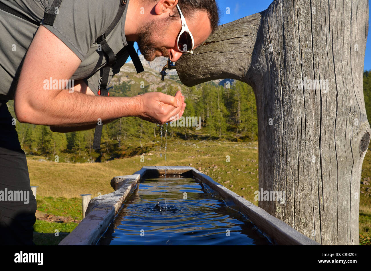 Wanderer selbst mit frischem Bergwasser aus Viehtränke, erfrischende Gotzenalm Alp, Schönau, Königssee Stockfoto