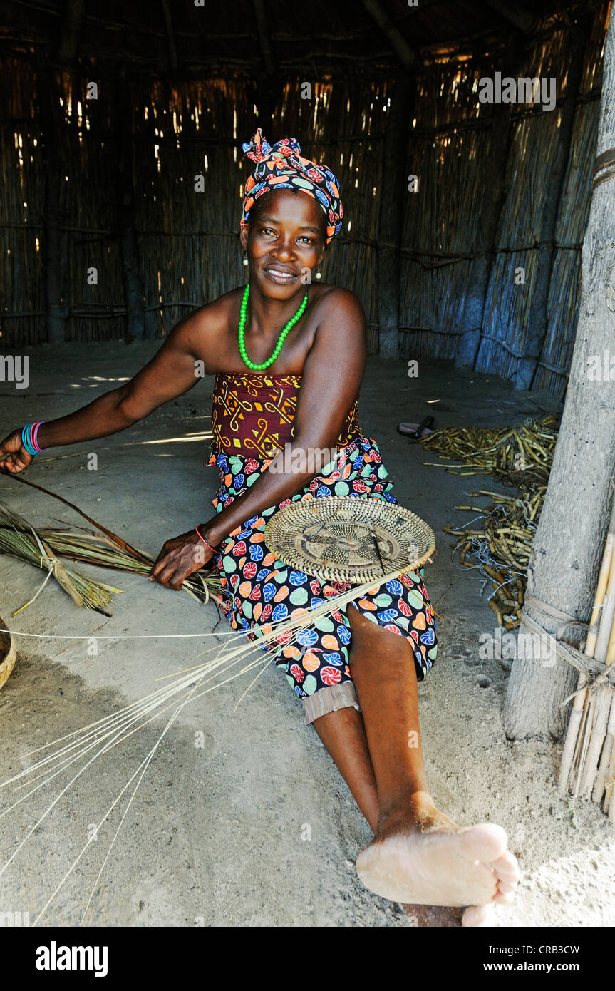 Frau zeigen in ihrer Hütte auf einer geführten Tour eines traditionellen Dorfes in der Nähe von Camp Kwando auf dem Kwando Fluss weben Stockfoto