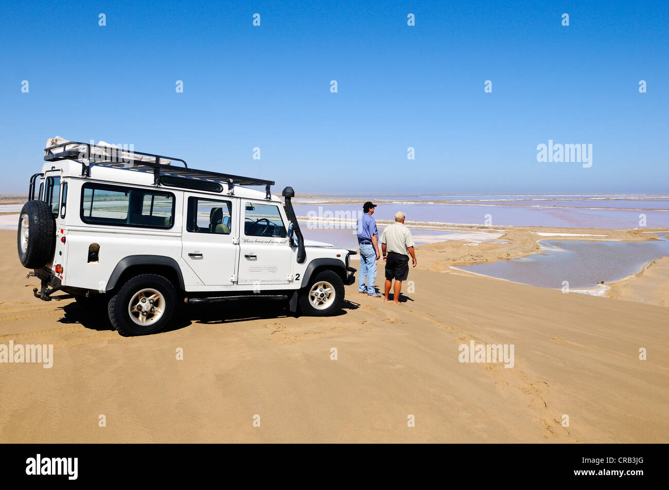 Männer mit einem Landrover Defender Geländewagen stand vor Wasserbecken zur Salzgewinnung, Nationalpark, Teil Stockfoto