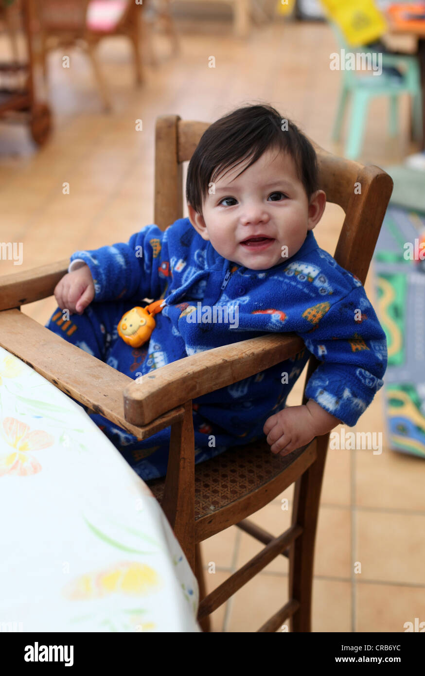 Es ist ein Foto von einem chinesischen eurasischen Mix Baby in einem alten Stil Babystuhl aus Holz machen. Er lächelt in die Kamera Stockfoto