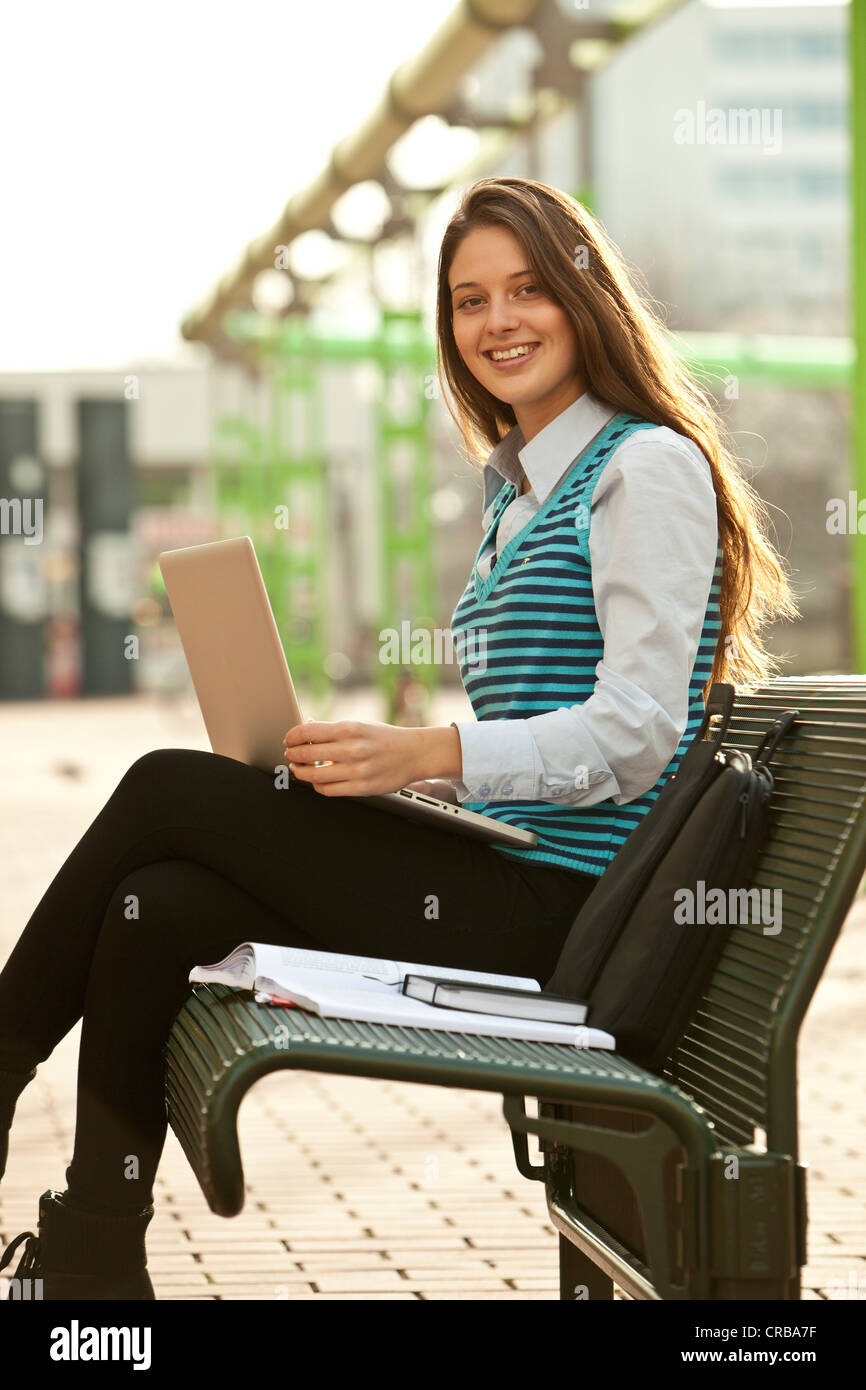 Student mit einem Laptop und einem Notebook sitzen auf einer Bank Stockfoto