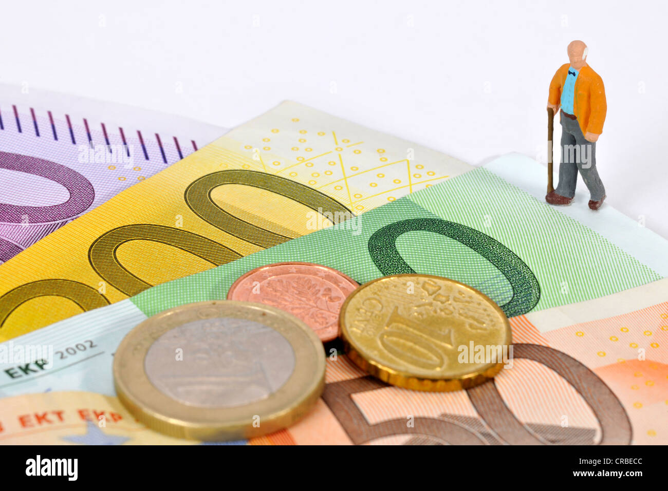 Miniatur-Figur von einem pensionierten Mann zu Fuß auf Euro-Banknoten und Münzen, symbolisches Bild für den Ruhestand, pension Stockfoto