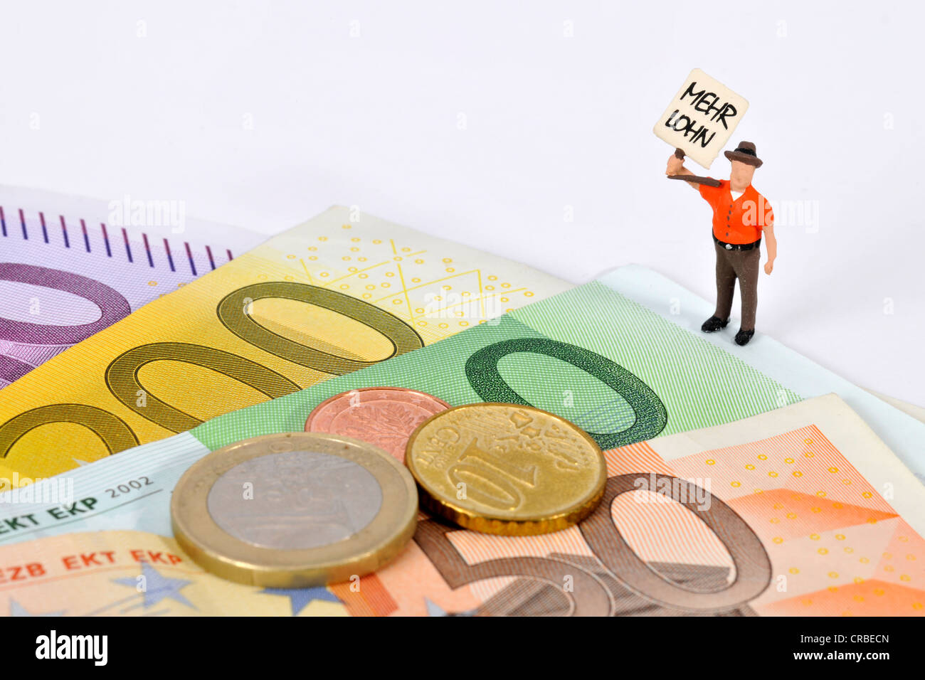 Miniatur-Figur mit einem Schild, Mehr Lohn, Deutsch für mehr zahlen, neben Euro-Banknoten und-Münzen Stockfoto