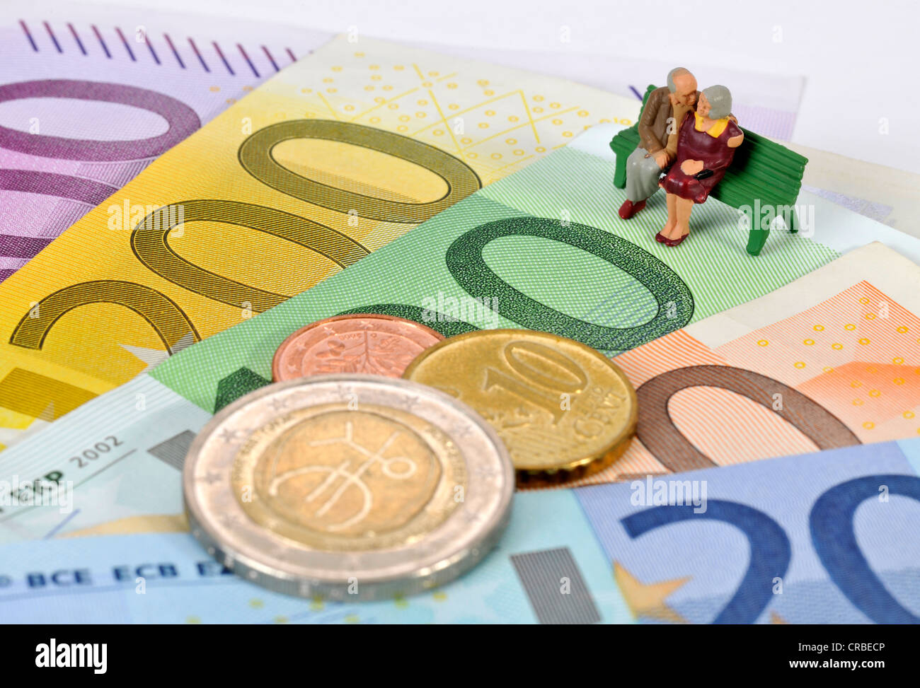 Miniatur-Figuren von einem Ehepaar im Ruhestand sitzt auf einer Parkbank auf Euro-Banknoten und Münzen, symbolisches Bild für den Ruhestand Stockfoto