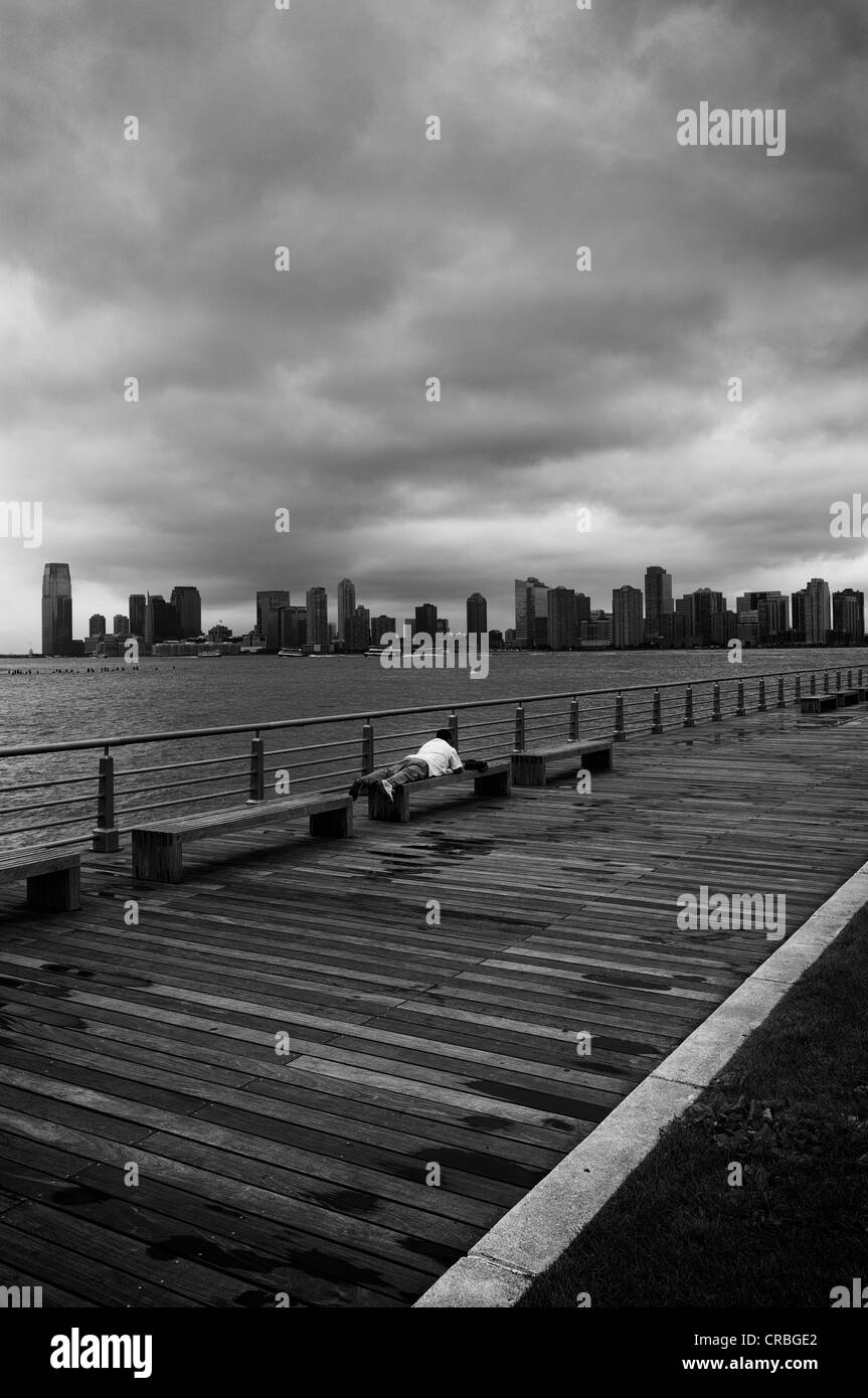 Koch, liegend auf einer Bank, Hudson River Greenway, Greenwich Village, Manhattan, New York City, New York, USA Stockfoto