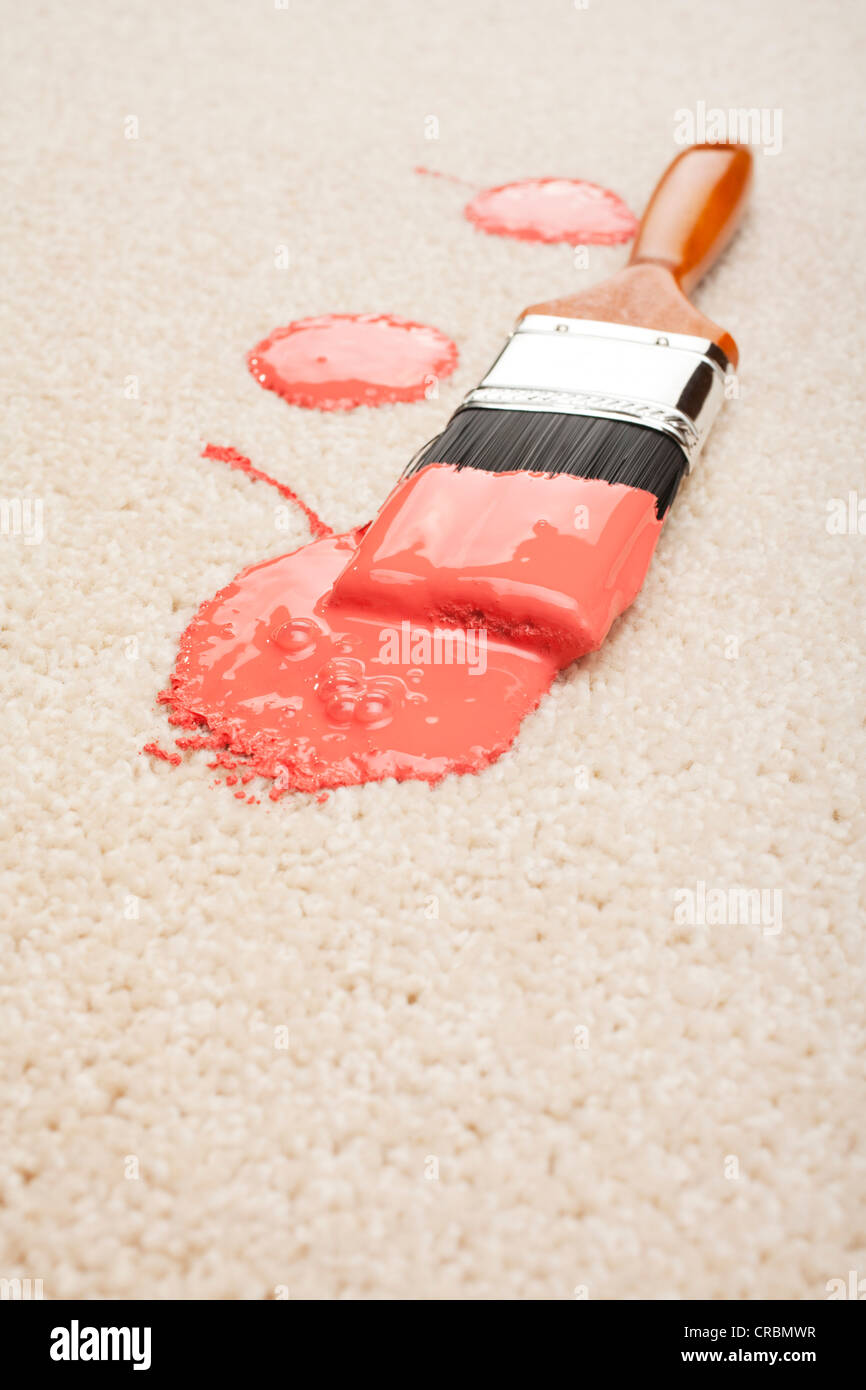 Verschüttete Farbe und Pinsel auf einem hellen farbigen Teppich. Stockfoto