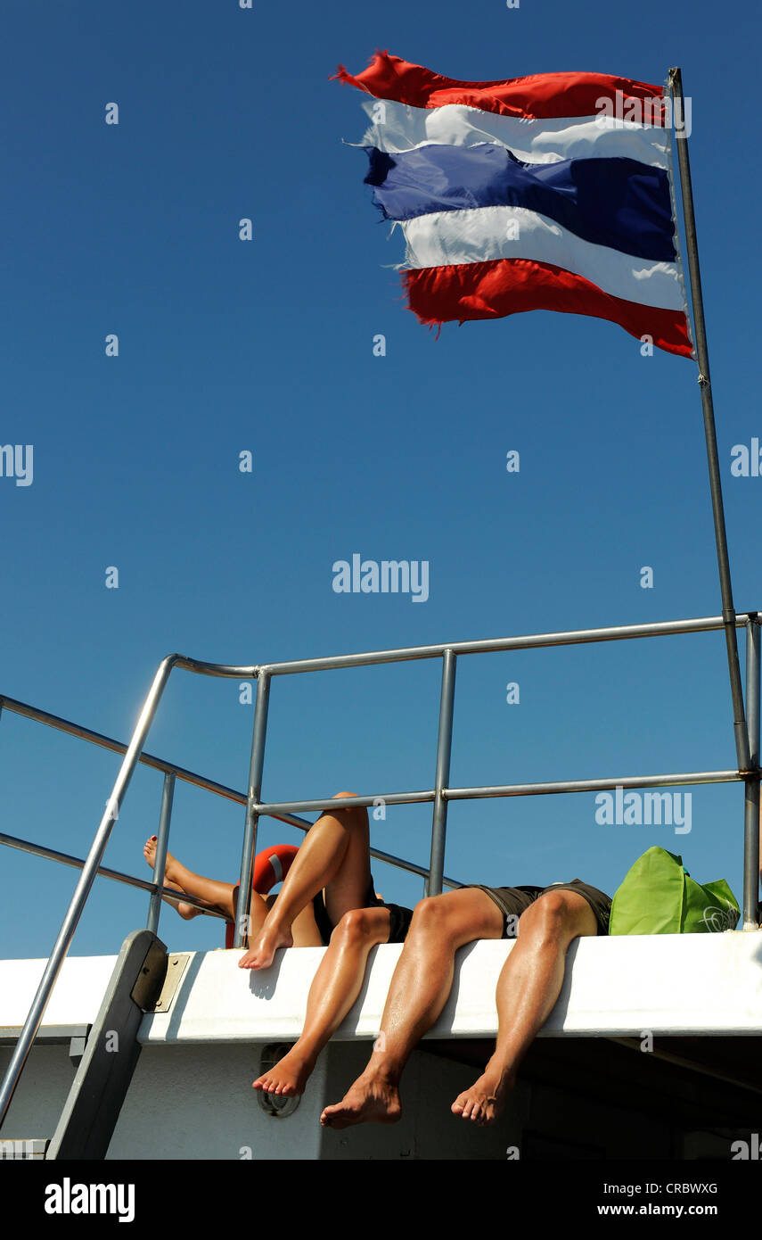 Touristen Sonnen ihre Beine auf einem Schiff fliegen die thailändische Flagge, Thailand, Asien Stockfoto