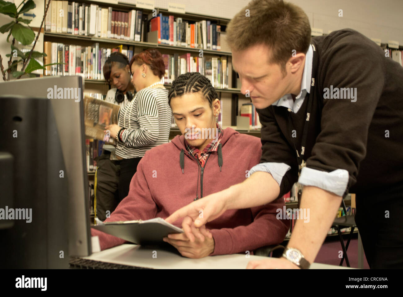 Lehrer helfen Schüler in Bibliothek Stockfoto