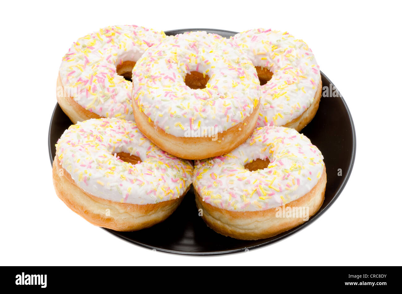 Ring-Donuts auf einer schwarzen Platte angeordnet. Studio mit einem weißen Hintergrund gedreht. Stockfoto