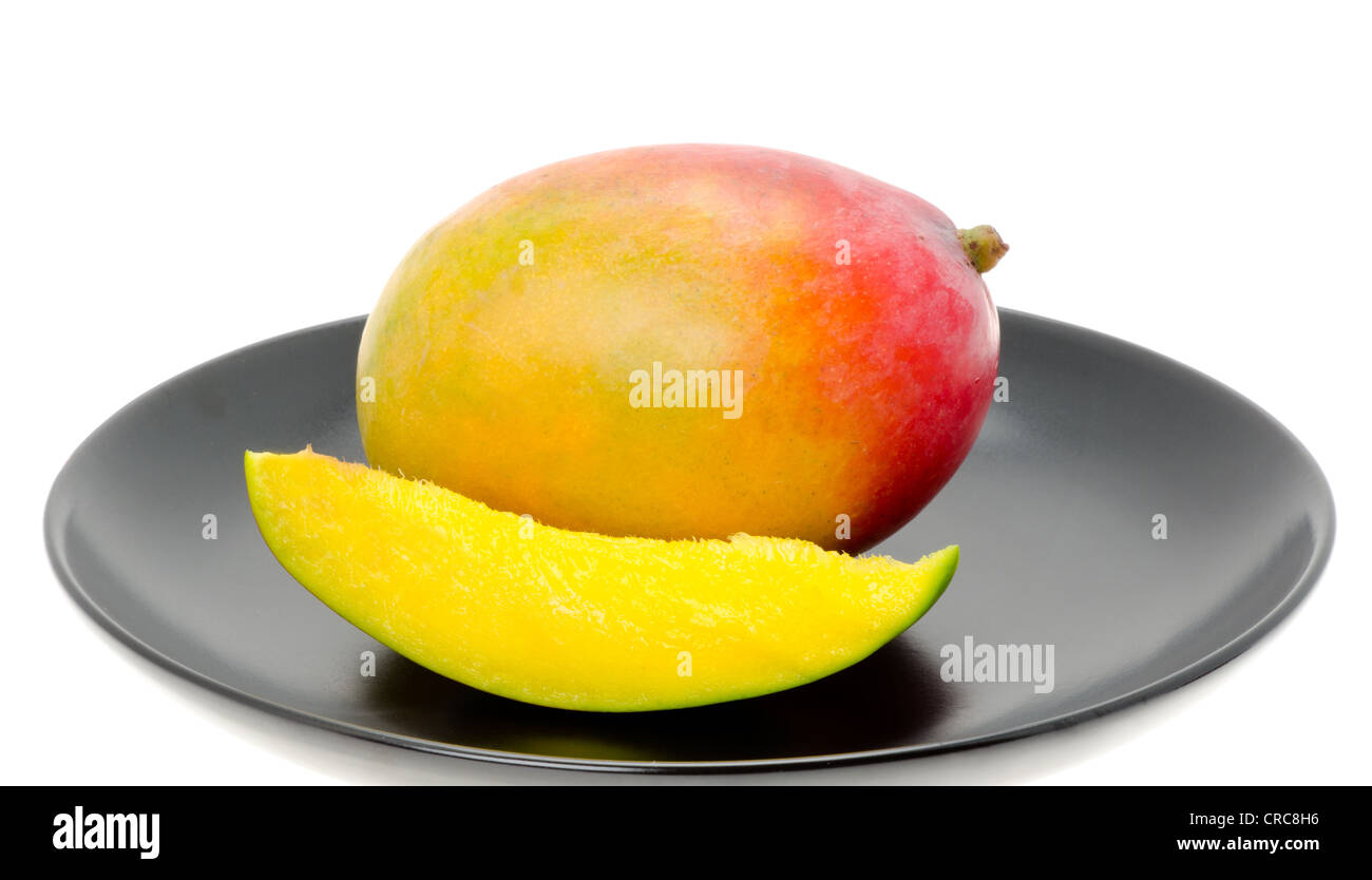Frische Mango-Frucht mit einer Scheibe von Mango auf einem schwarzen China Teller. Studio mit einem weißen Hintergrund gedreht. Stockfoto