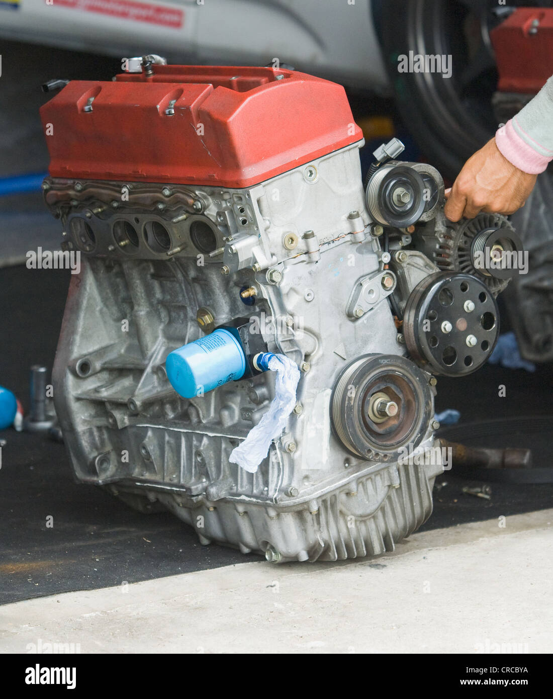 Vierzylinder-Automotor auf dem Boden. Hand des Mechanikers sichtbar. Stockfoto