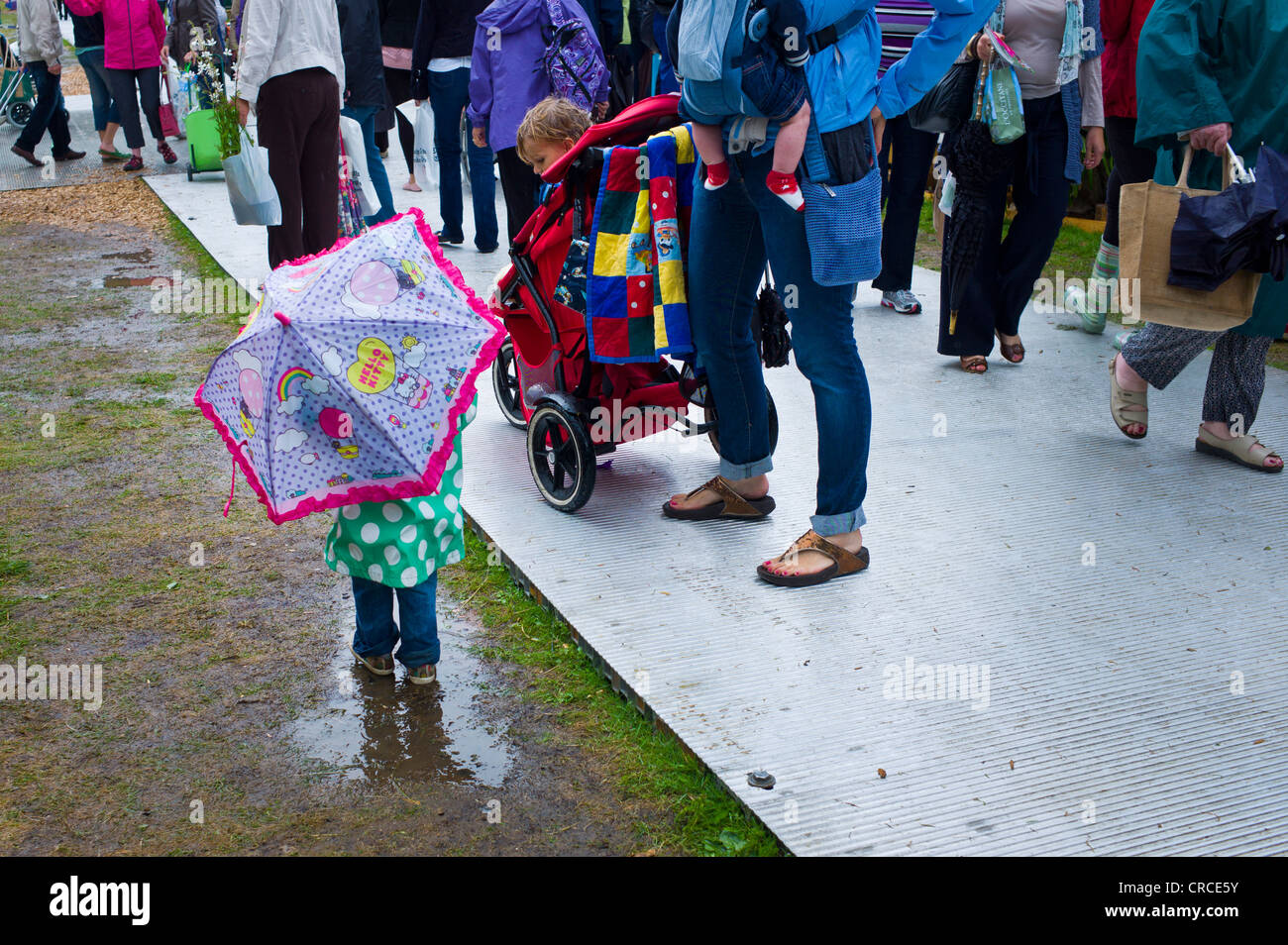 Ein Kleinkind unter einem Regenschirm spielt in einer Pfütze bei RHS Hampton Court Flower Show 2011 Stockfoto