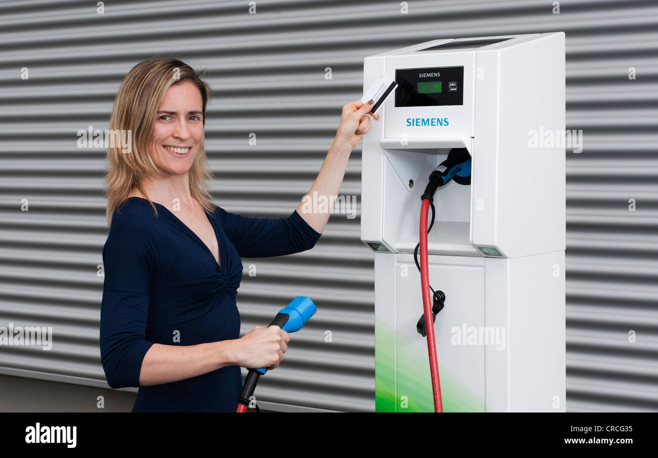 Frau hält eine Codekarte vor dem Leser von einer Charge CP700A Ladestation von Siemens, Fürth, Bayern Stockfoto