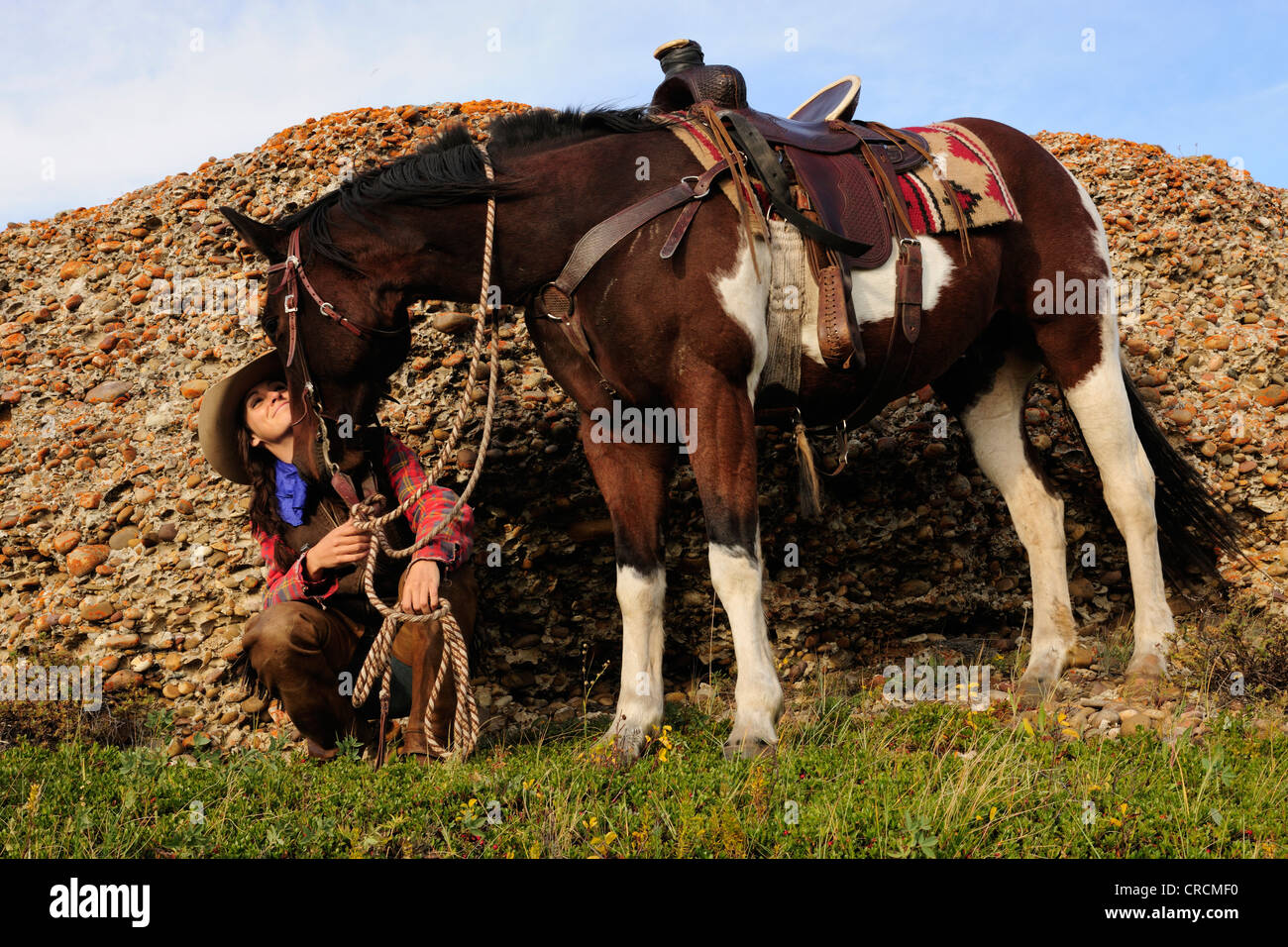 Cowgirl posiert vor einer Wand des Felsens, die Zügel der ihr Pferd, Saskatchewan, Kanada Stockfoto