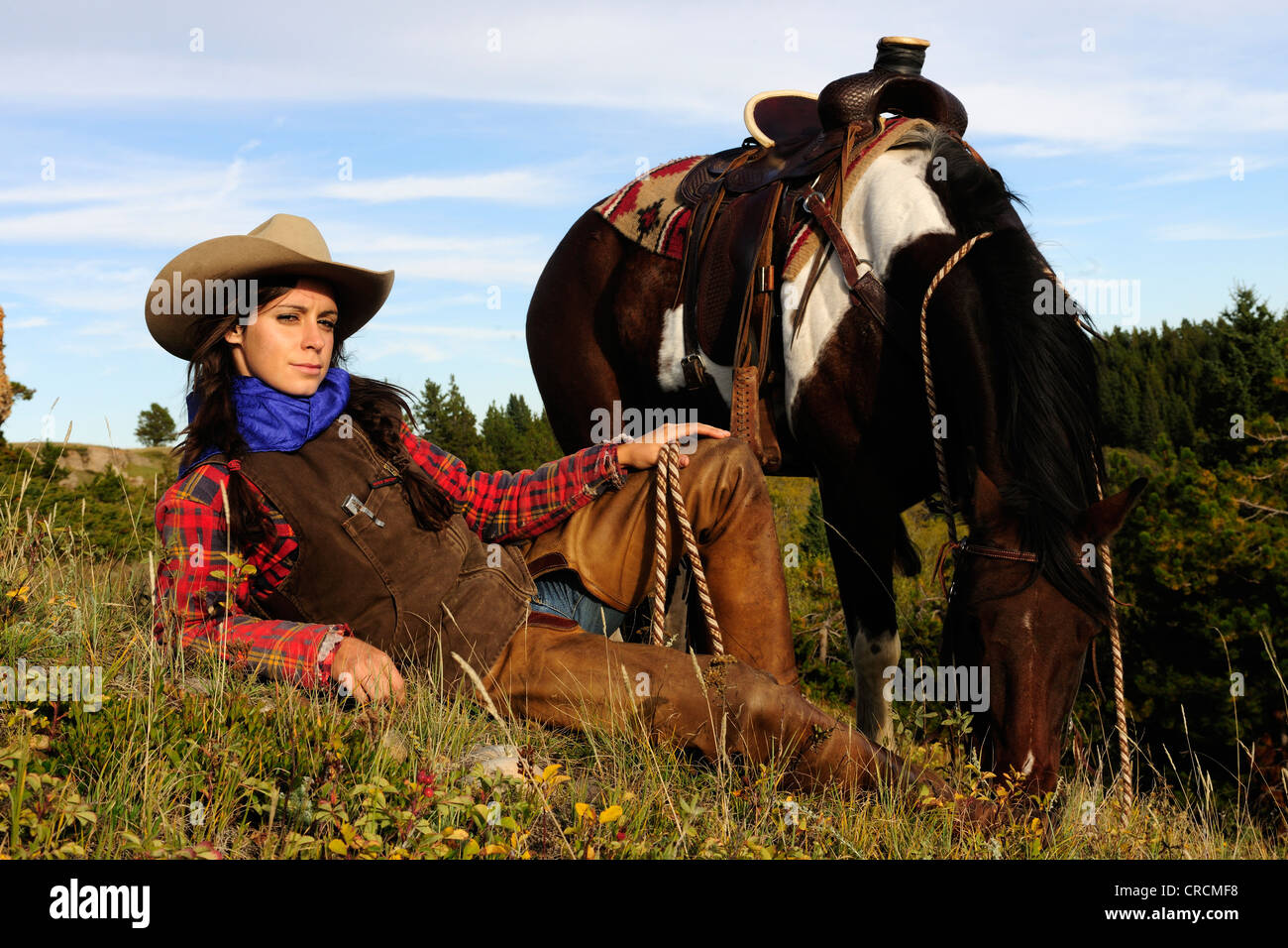Cowgirl liegen in der Wiese, ihr Pferd stand neben ihr, Saskatchewan, Kanada Stockfoto