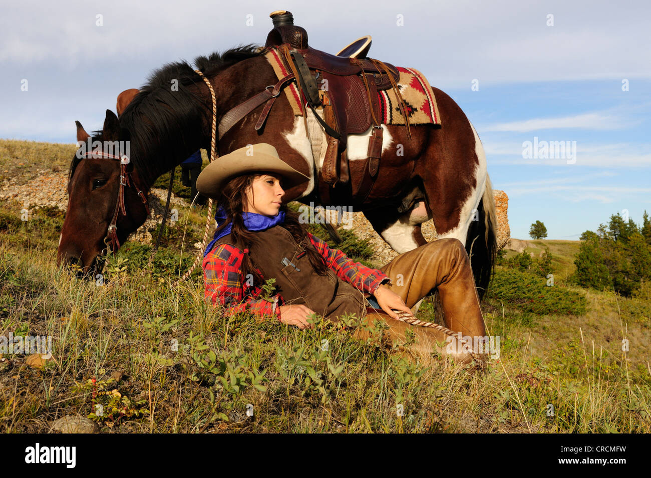 Cowgirl liegen in der Wiese, ihr Pferd stand neben ihr, Saskatchewan, Kanada Stockfoto