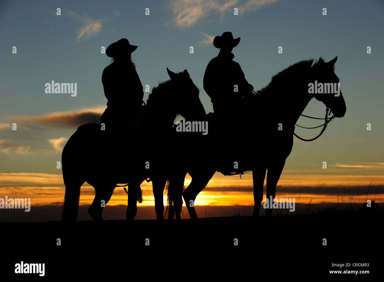 Cowgirl und Cowboy sitzt auf dem Pferderücken bei Sonnenuntergang, Saskatchewan, Kanada, Nordamerika Stockfoto