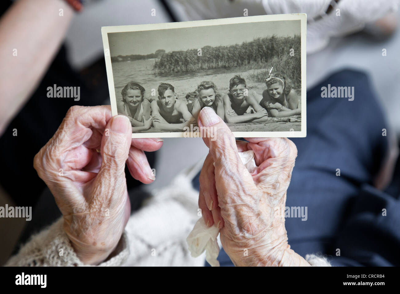 Altes Foto, alte Dame Hände halten eine historische schwarz-weiß Fotografie von 1940, Erinnerungen, historisches Foto anzeigen Stockfoto