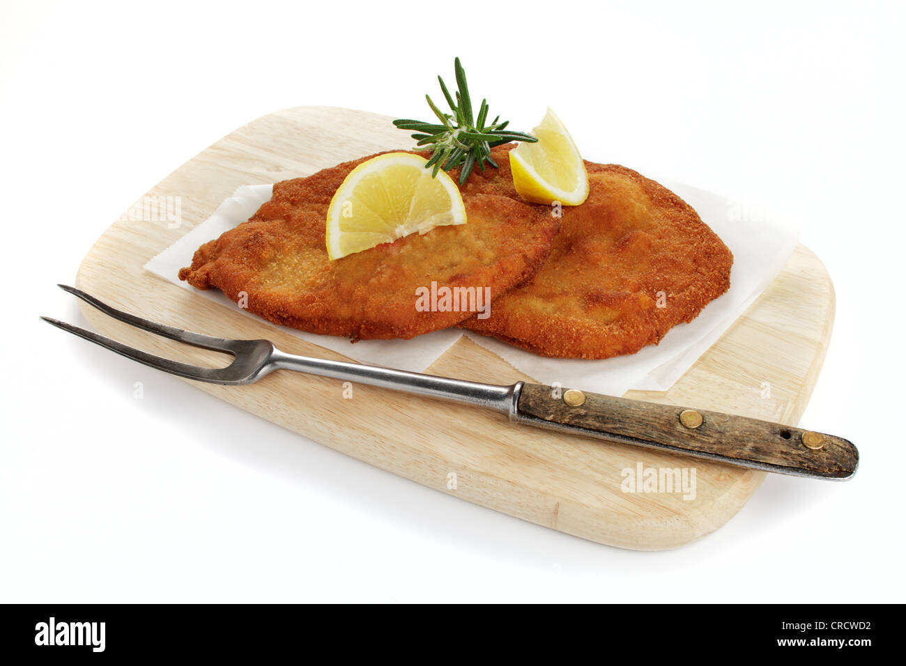 Wienerschnitzel mit Zitronenspalten auf einem Holzbrett Stockfoto