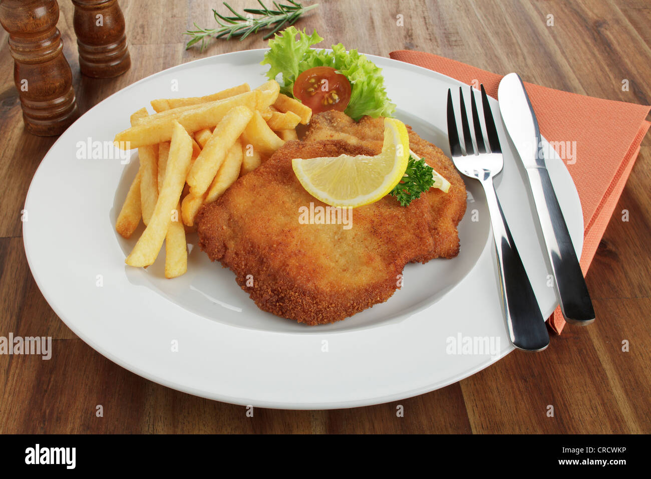 Paniertes Schweinefleisch Schnitzel Wiener Art mit Zitronenscheibe und Pommes frites Stockfoto