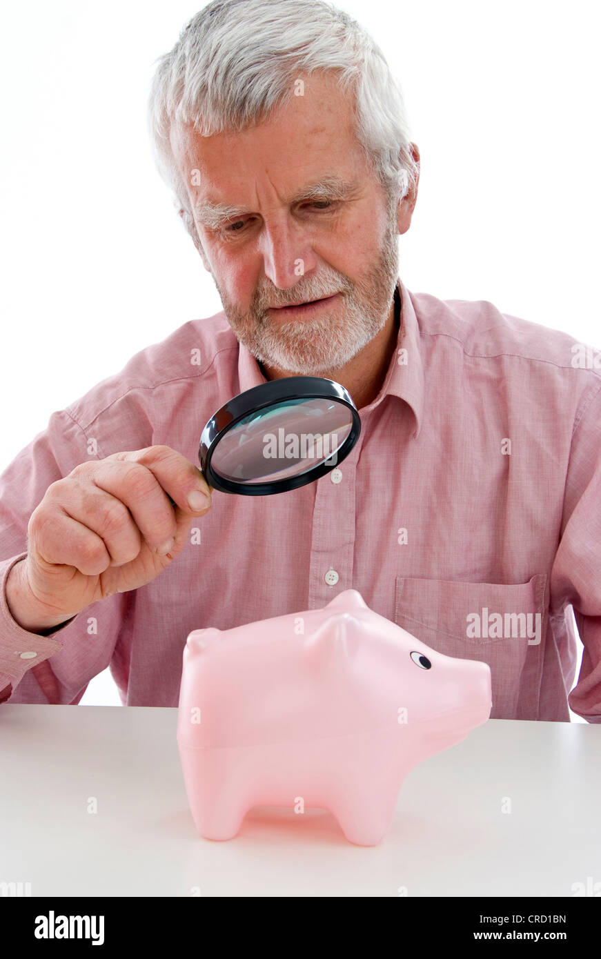 Rentner, die gerade Piggy Bank unter der Lupe Stockfoto