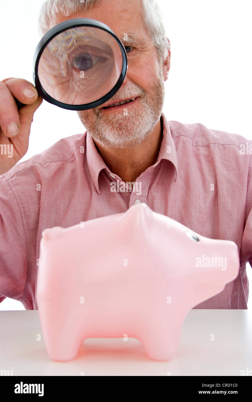 Rentner, die gerade Piggy Bank unter der Lupe Stockfoto