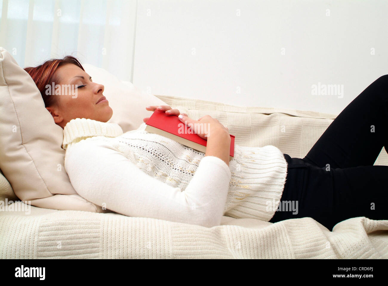 junge Frau mit Buch, schlafen auf der couch Stockfoto