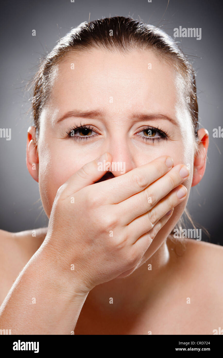 Junge Frau hält eine Hand auf ihren Mund Stockfoto