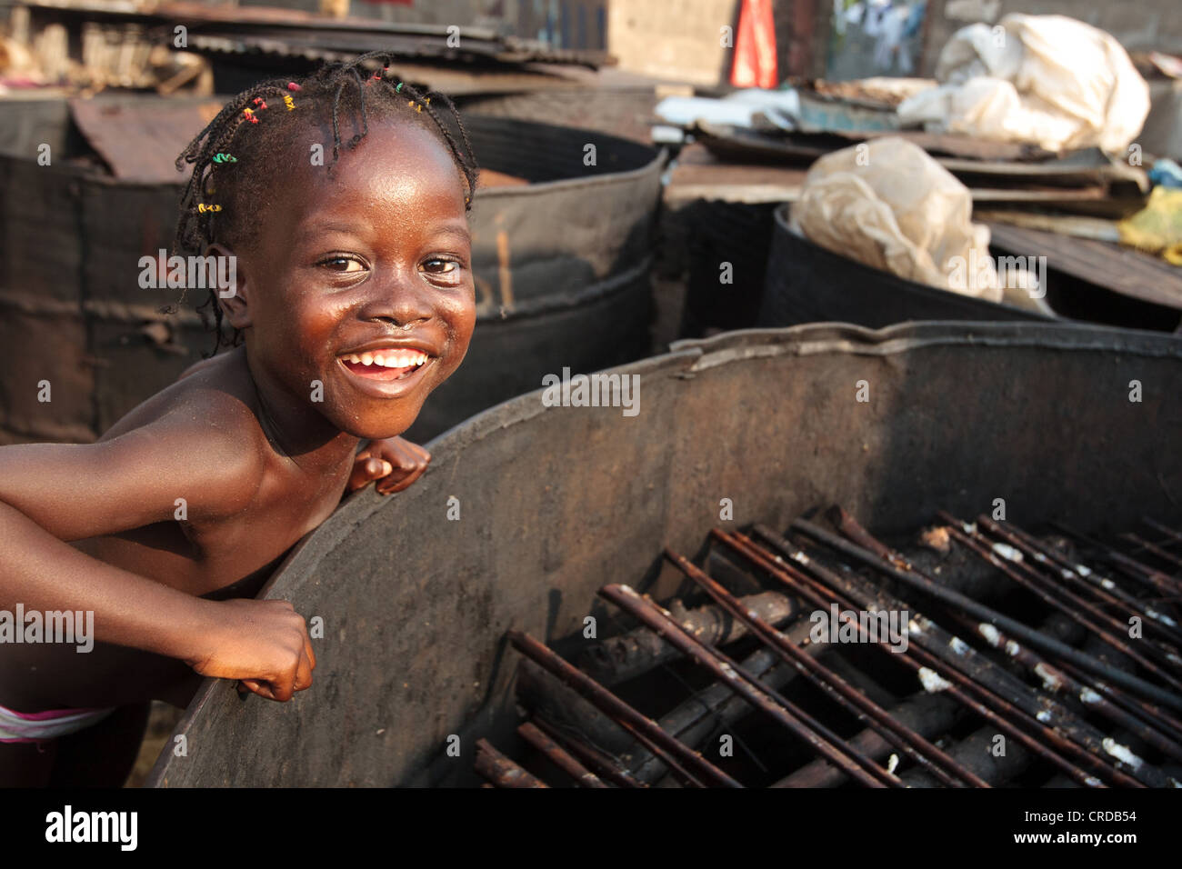 Eine Mädchen steht neben einem großen Fass verwendet, um die Fische in den Westpunkt Slums von Monrovia, Liberia auf Monda Montserrado County Räuchern Stockfoto