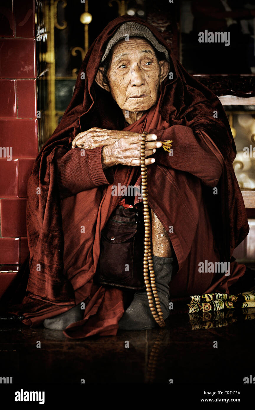 Alte buddhistische Nonne sitzen mit Gebetskette auf die Mahamuni Pagode in Mandalay, Myanmar, Birma, Südostasien, Asien Stockfoto